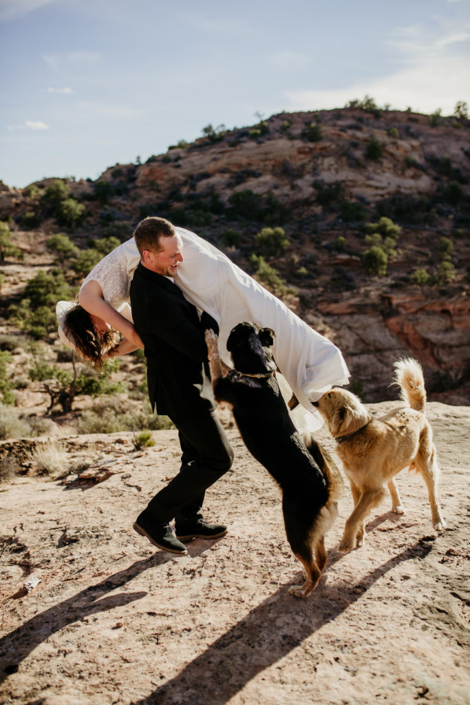 The best desert elopement location is Moab, Utah. You can get married in the dessert under the stars. Canyons and pink sunsets with bride and groom. Wedding with dogs in Moab.