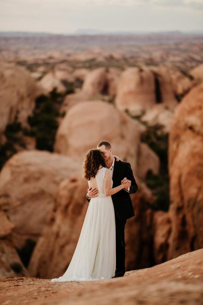 The best desert elopement location is Moab, Utah. You can get married in the dessert under the stars. Canyons and pink sunsets with bride and groom. 