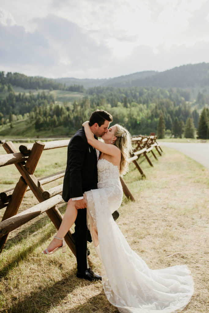 Couple at 320 Guest Ranch in Big Sky, embracing on their wedding day next to a fence.