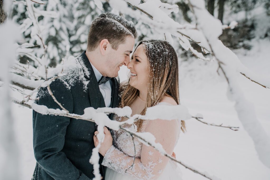 Couple touching noses in a snow wedding.