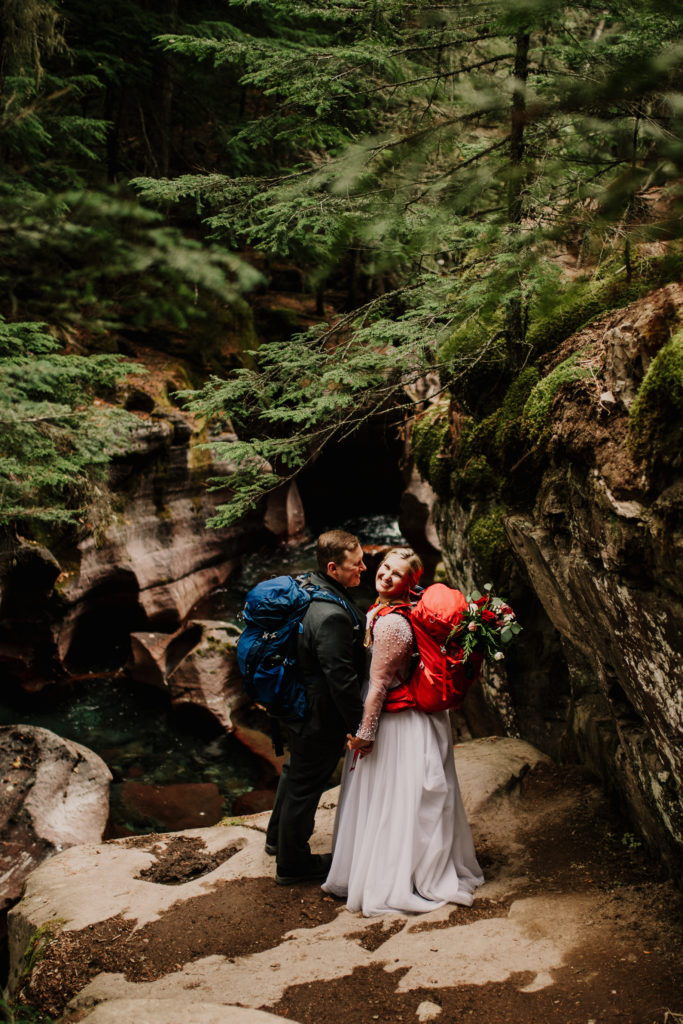 Have an eco friendly elopement by following these tips for conscious tourism.

Hiking elopement couple hike with their wedding clothes and backpack. Glacier National Park hiking elopement. 