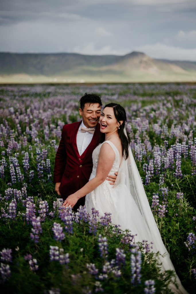 Best of 2022 elopement & wedding photography, Iceland elopement photography at Reynisfjara black sand beach. Elopement photos taken at Skogafoss waterfall. Wedding photos with lupine in Iceland. 