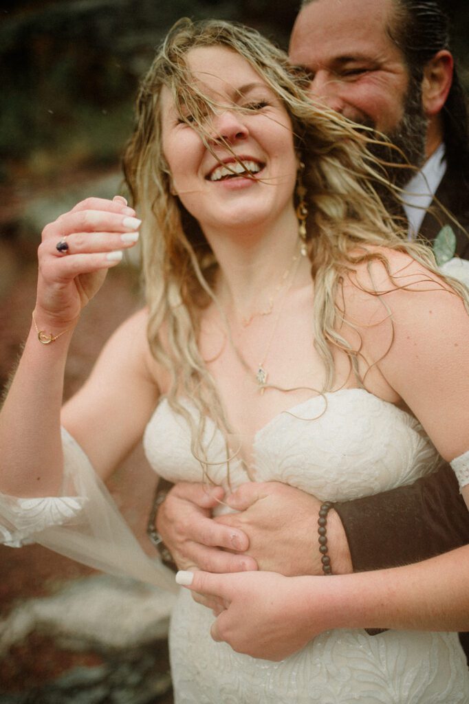 Many Glacier Lodge Micro Wedding groom holding bride as she smiles with hair in her face
