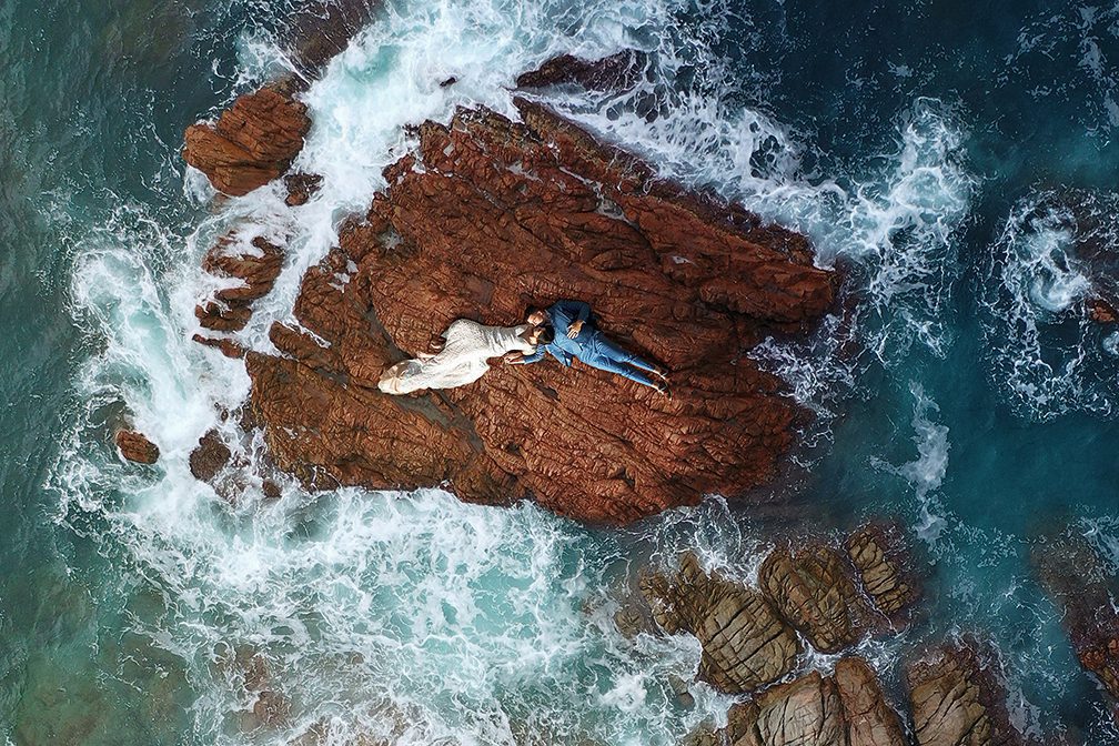 Part one of our Ultimate 2024 Greece Guide, Elope in Greece breaks down the cost, legality, planning and outlines a two day Greece elopement.

bird eye shot of couple laying on rock surrounded by water