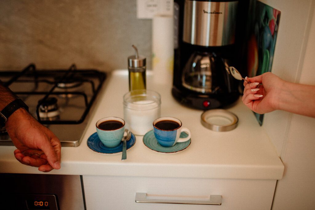 photo of two filled coffee cups and two hands reaching into the frame to make a coffee. A habit for elopement photographer mindset.