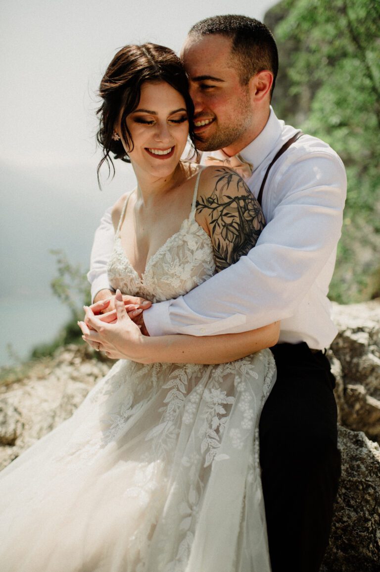 Costa Brava elopement with husband holding wife from behind. Couples smiling in embrace.