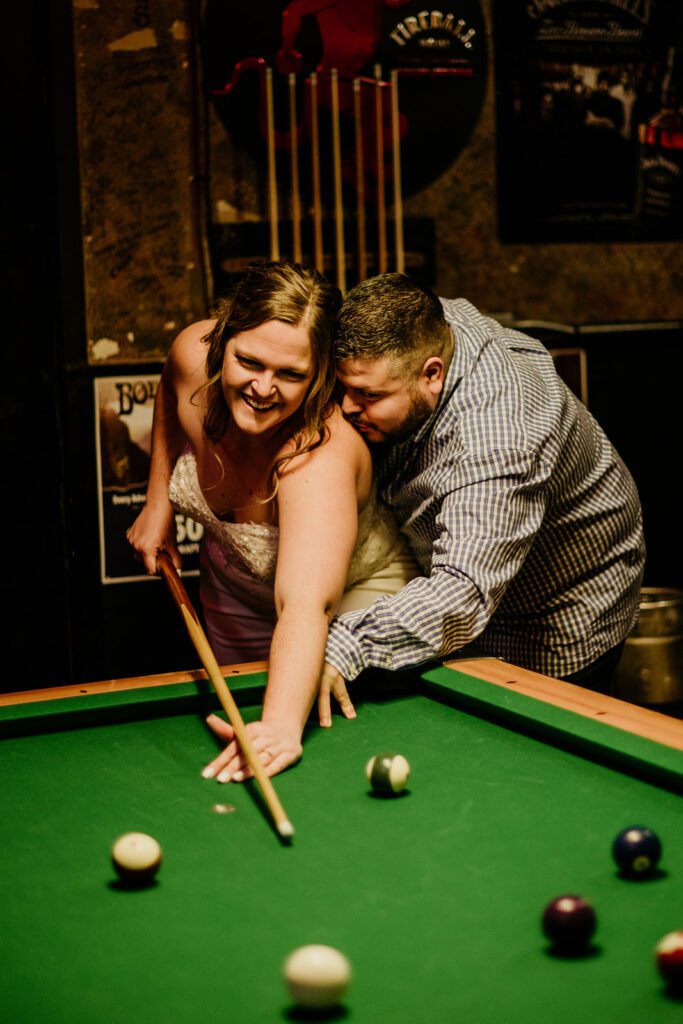 A man nuzzles up to a woman during a game of pool during this engagement photos in Missoula.