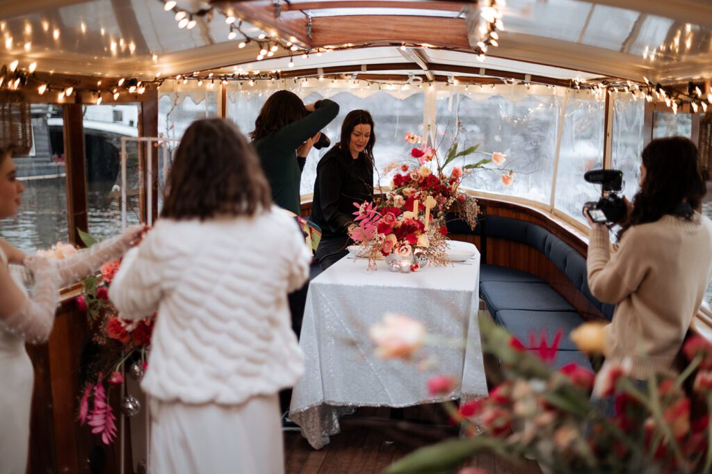 Photographer building up her associate team with a group of photographers taking photos in a boat in Amsterdam. Beautiful florals and twinkling lights.