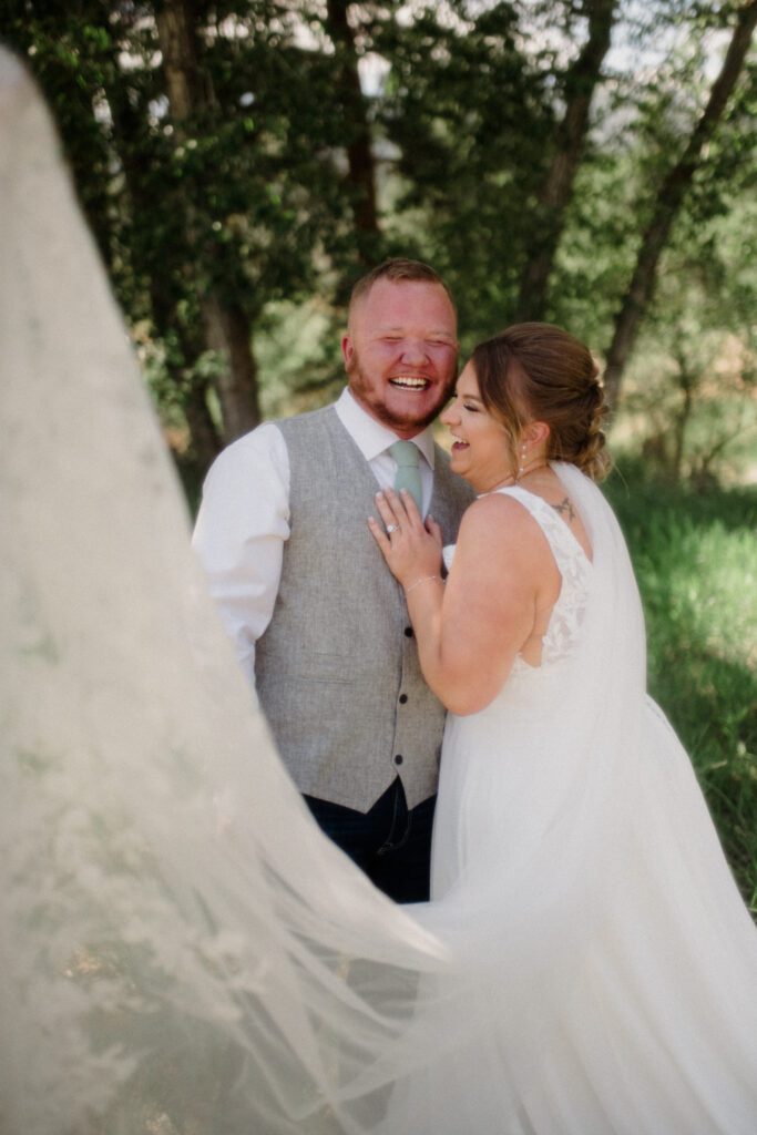 Montana elopement guide with husband and bride laughing on wedding day in front of trees.