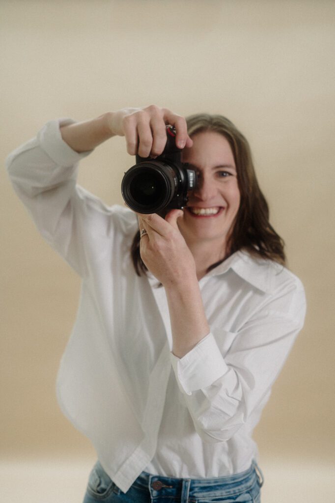Make More Money as a Wedding Photographer! Photo of photographer in white portfolio shirt holding a camera.
