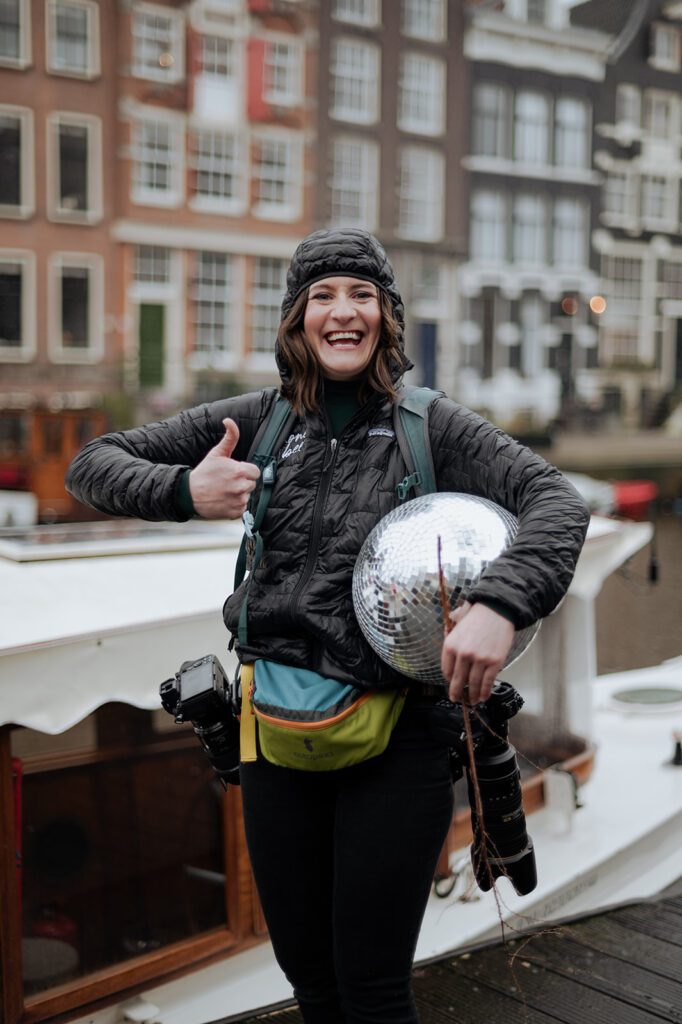 KPIs as a photographer, photographer in Amsterdam in rain gear, holding a disco ball and giving a thumbs up.