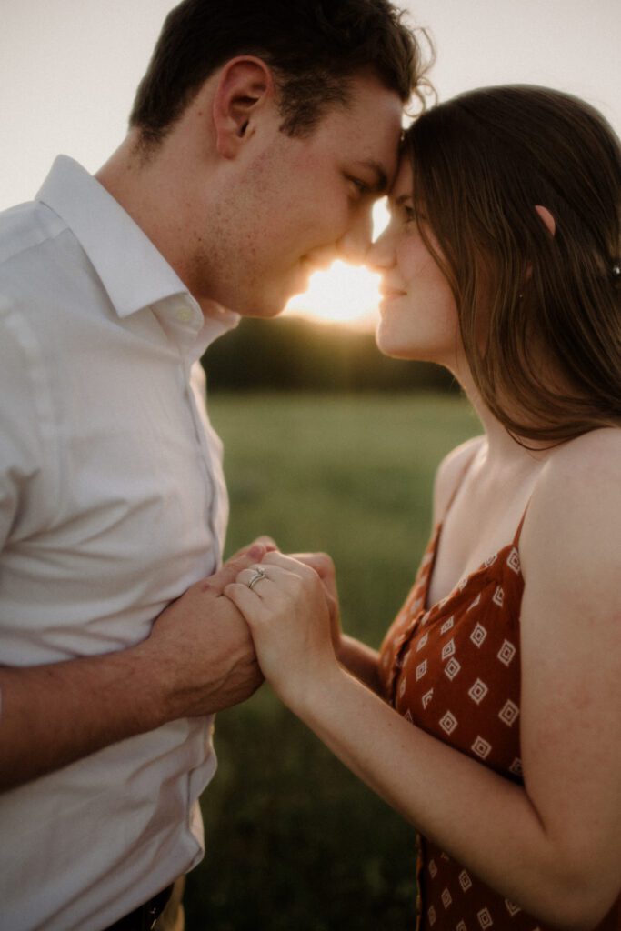 A couple laughs while looking at each other during engagement photos in Missoula. A river is behind them and trees are featured.