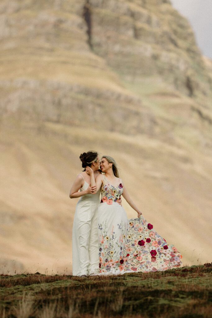 Iceland Queer Elopement on the Snaefellsness Peninsula. Two brides embracing with epic mountain in the background.