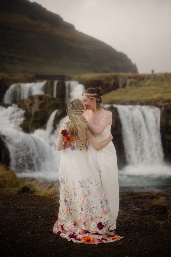 Iceland Queer Elopement on the Snaefellsness Peninsula. Queer couple in front of Iceland waterfall, pulling each other in for a kiss.