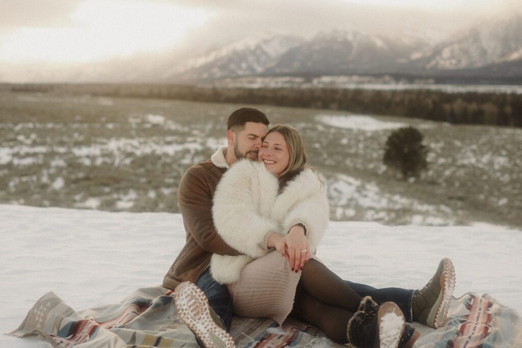 Grand Teton mountains behind newly engaged couple after a snowy proposal