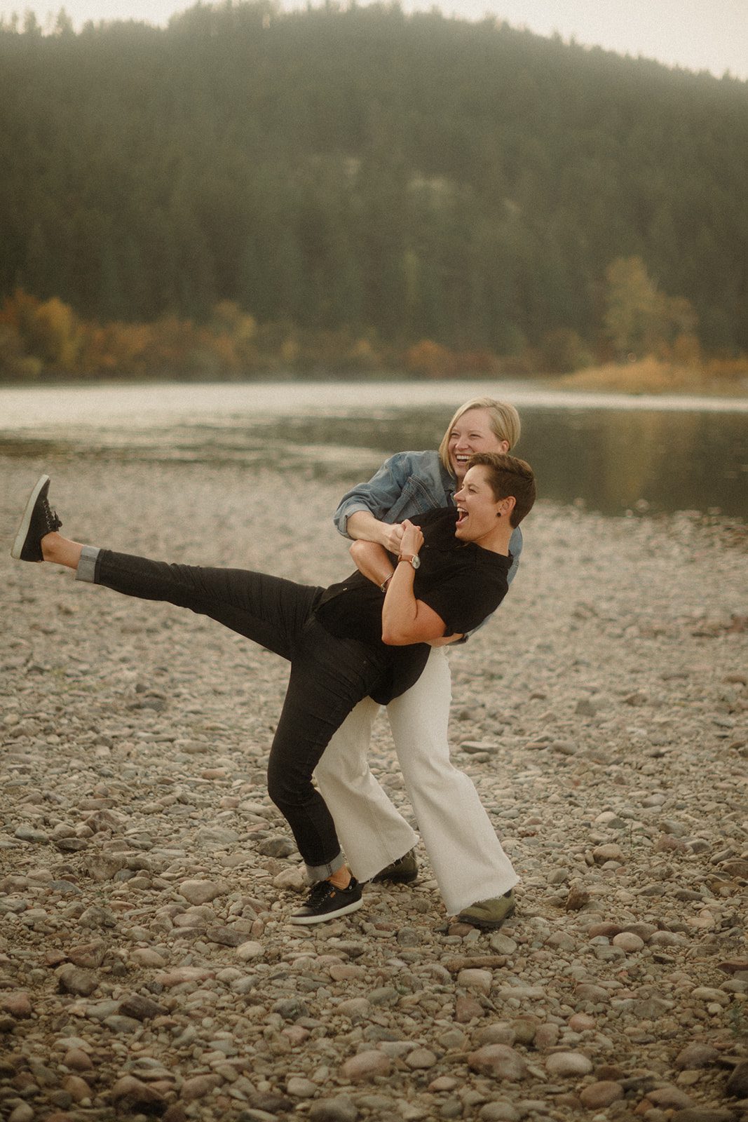 Lesbian Proposal in Missoula: Maclay Flat in Autumn. Woman dipping her partner on the Maclay shoreline, both women laughing. 