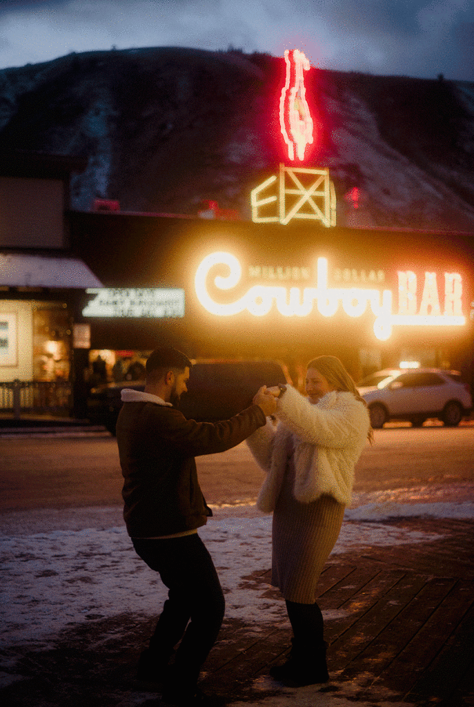 Couple dancing at dusk in Jackson Hole, Wyoming. Country Bar illuminated behind them. 