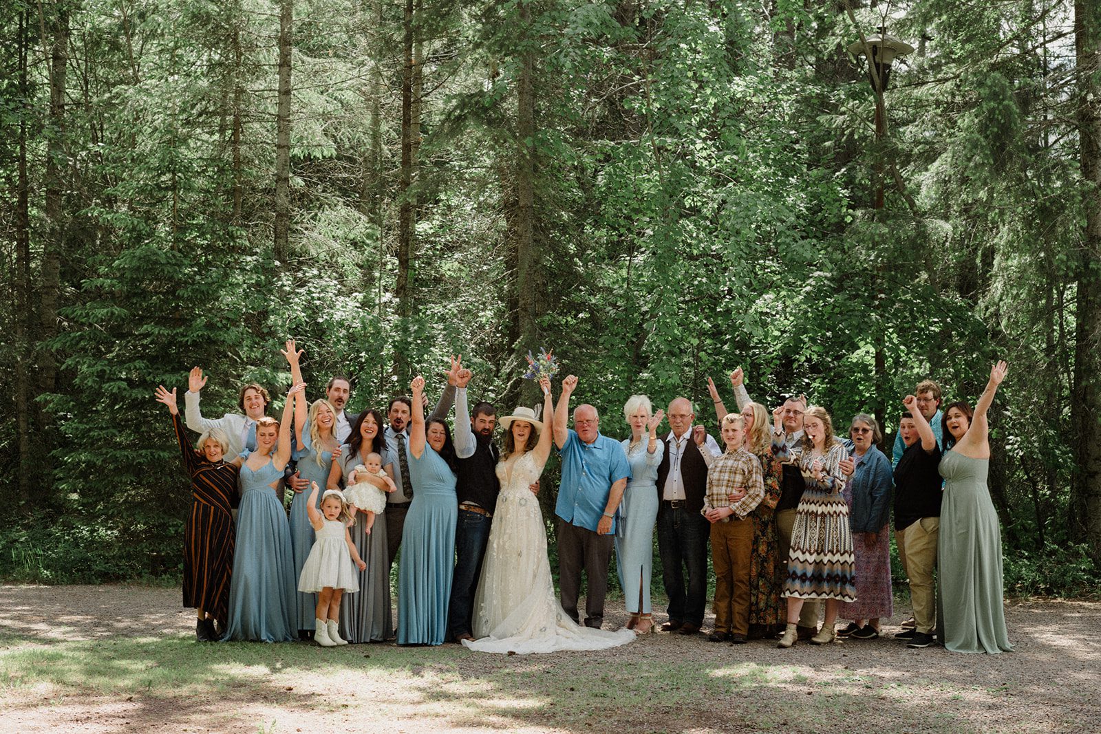 How to have a micro wedding in Glacier National Park with 30 friends and family. Couple and wedding guests in front of trees in celebration.