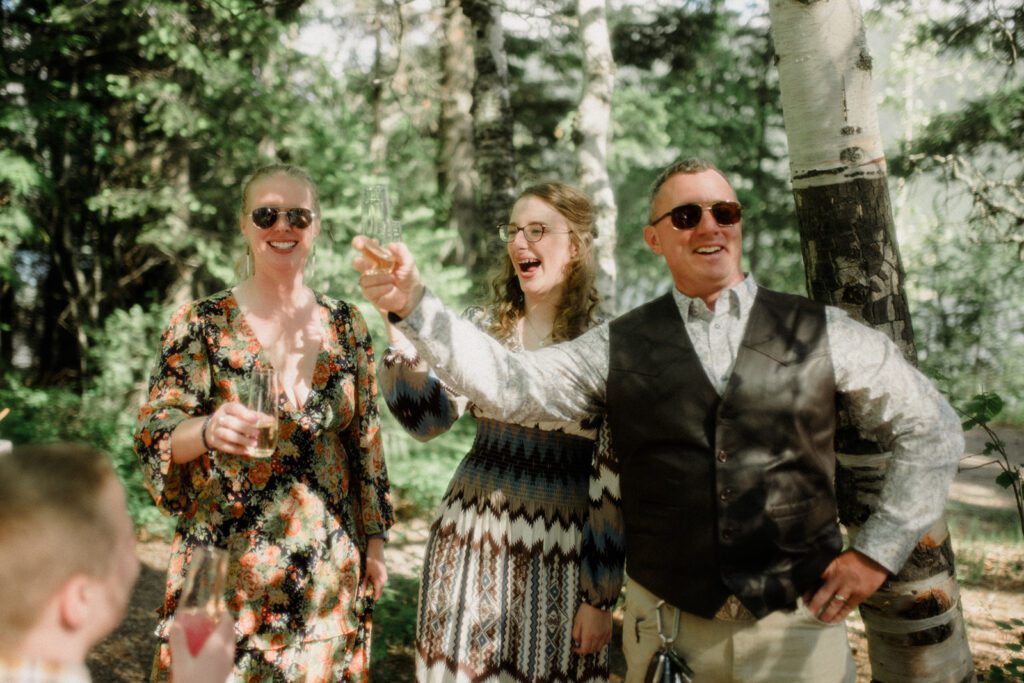 How to have a micro wedding in Glacier National Park with 30 friends and family. Couple and wedding guests in front of trees in celebration.