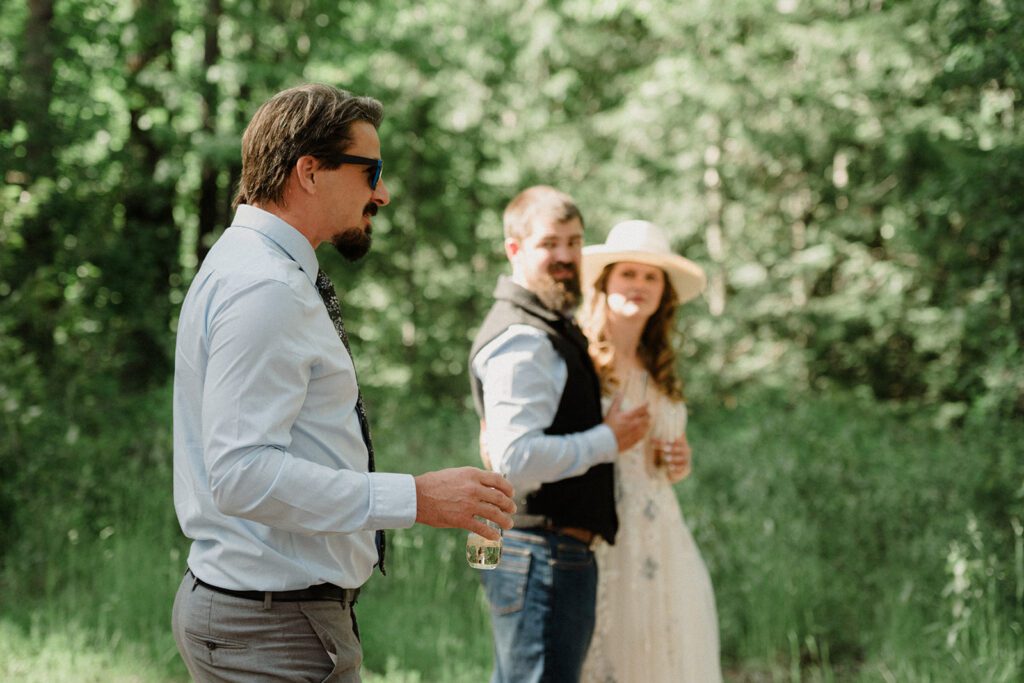 How to have a micro wedding in Glacier National Park with 30 friends and family. Couple and wedding guests in front of trees in celebration.