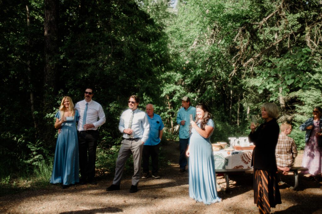 How to have a micro wedding in Glacier National Park with 30 friends and family. Couple and wedding guests in front of trees in celebration.