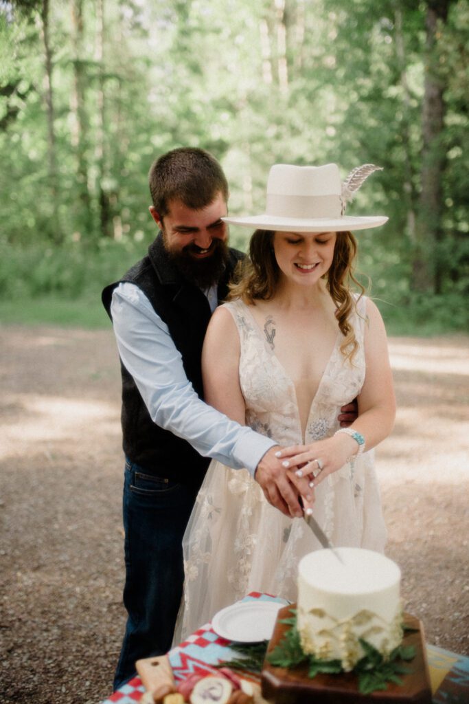 Couple cutting wedding cake in Glacier National Park during their micro wedding.