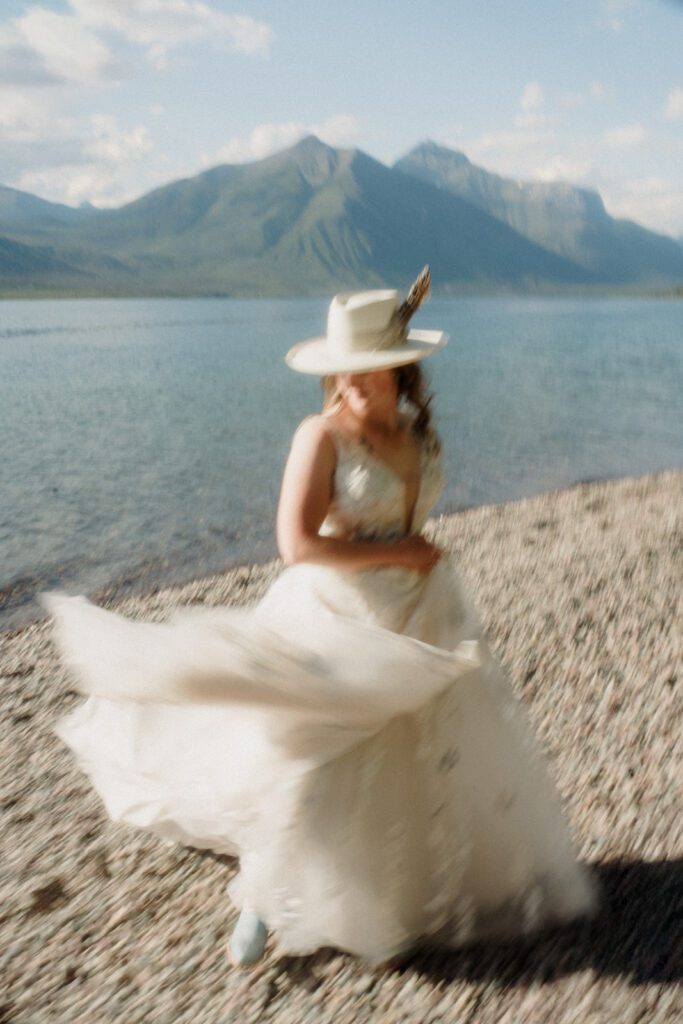 Blurred photo of bride on shores of Lake McDonald twirling her wedding dress.