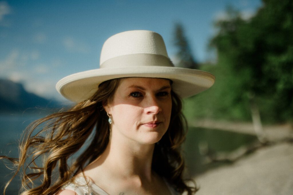 Close up of bride in hat with hair blowing in the wind.