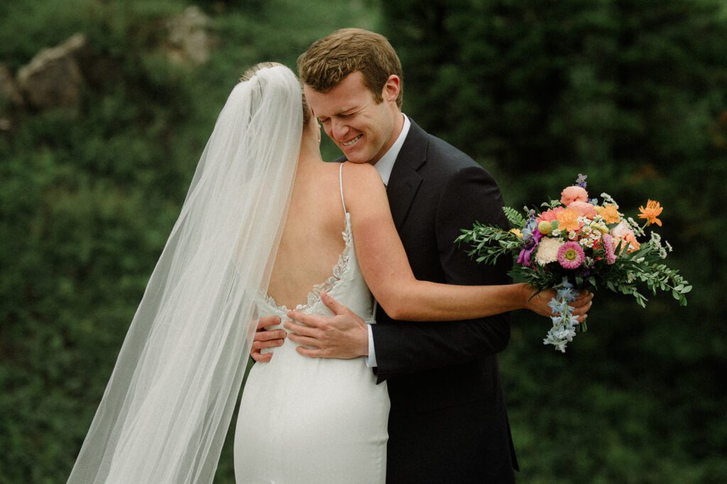 Groom holding bride and crying on wedding day.