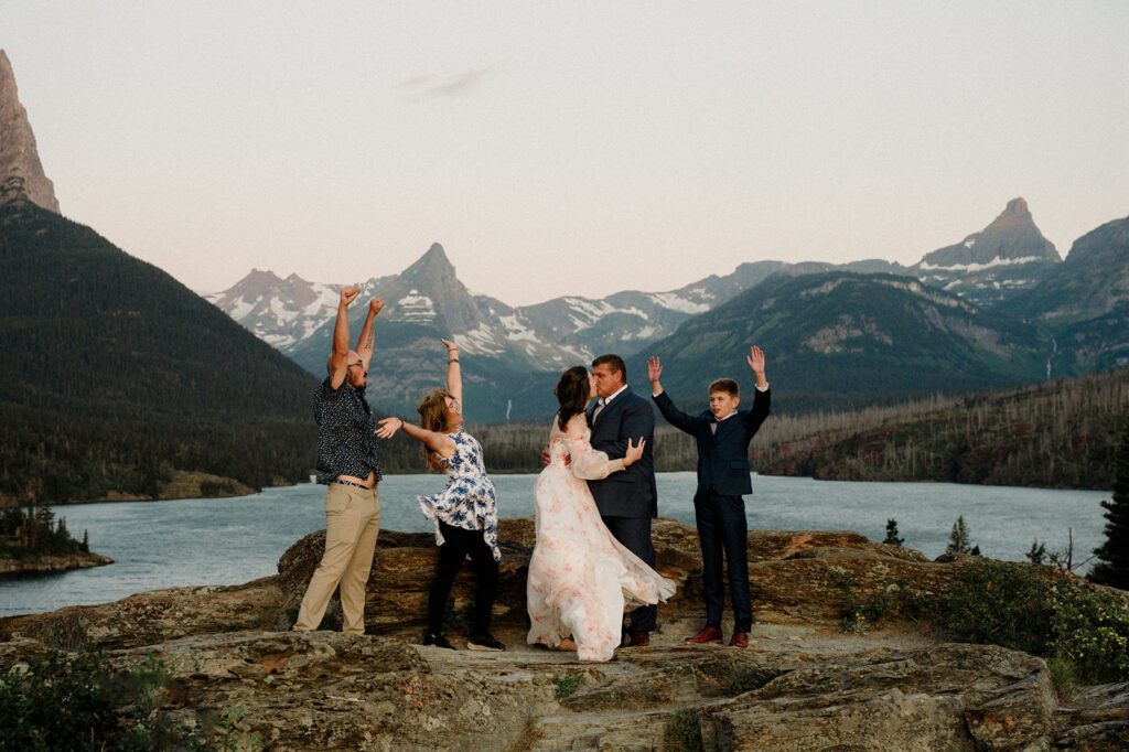 Sun Point Micro Wedding sunrise photo of bride and groom kissing with family celebrating around them. 