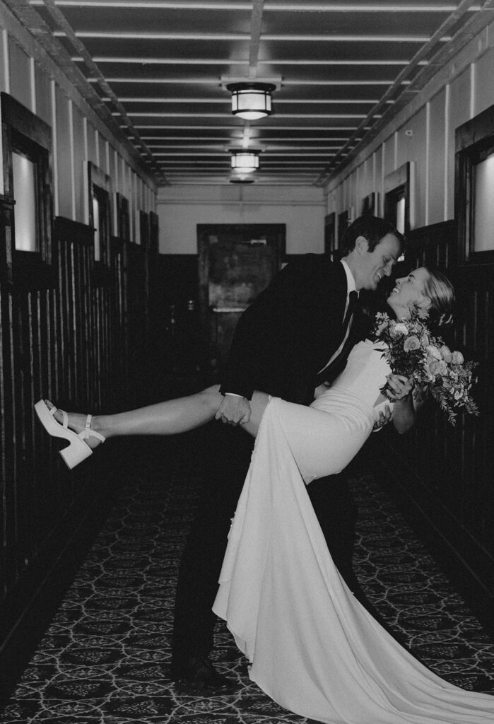 Wedding couple in Many Glacier Hotel, shows grooms hand on bride's thigh. Black and White.