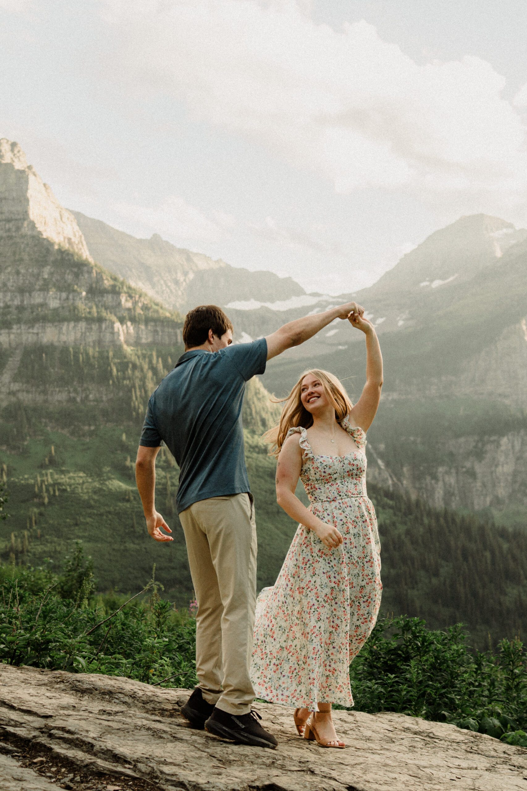 Man twirling woman during their Glacier National Park engagement session! They romped around the amazing Going-to-the-Sun Road, and some of the highlights are in Logan Pass! The best of 2025 Elopement & Wedding Photography.