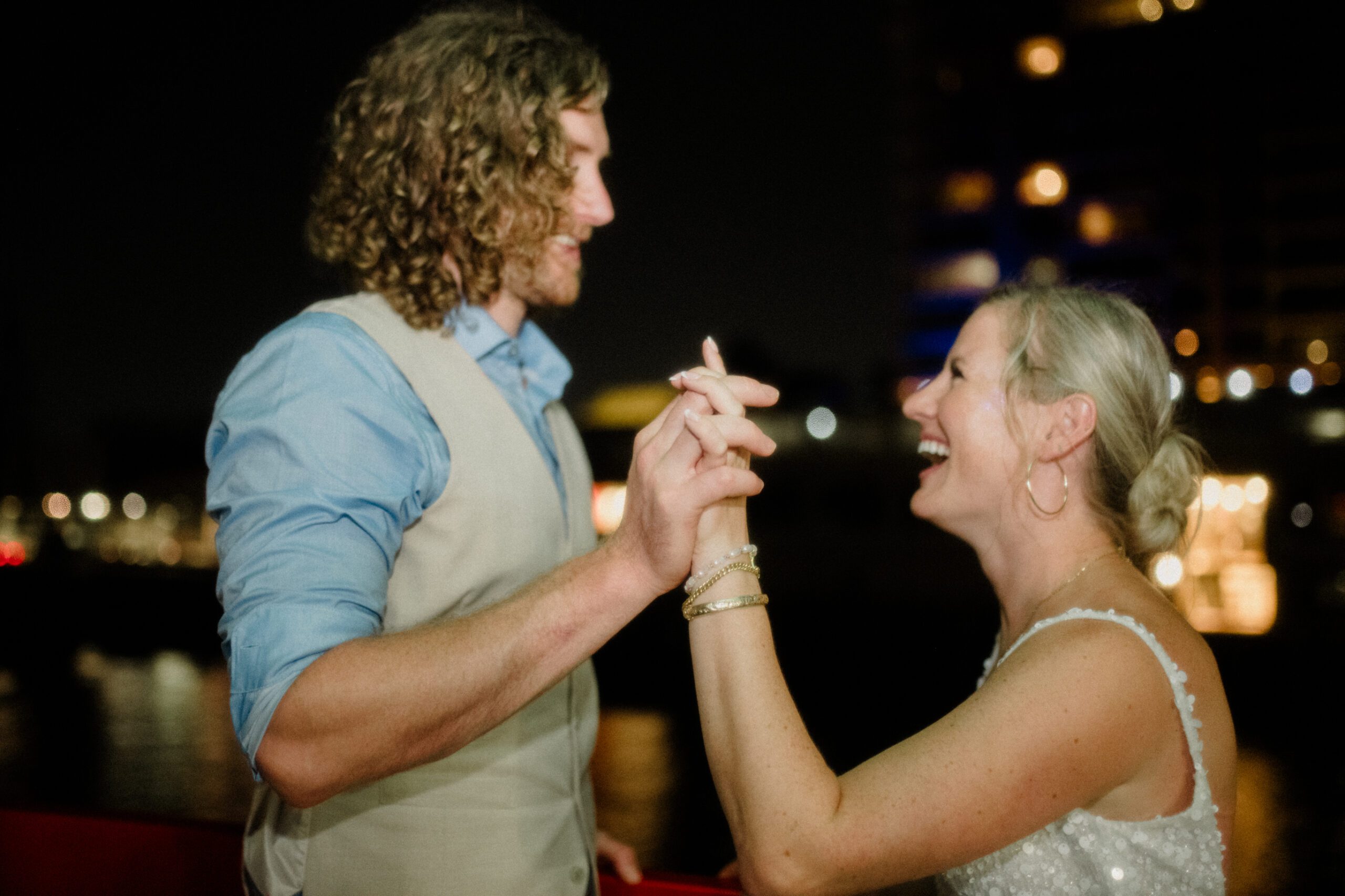 Couple holding hands in laughter on wedding night.