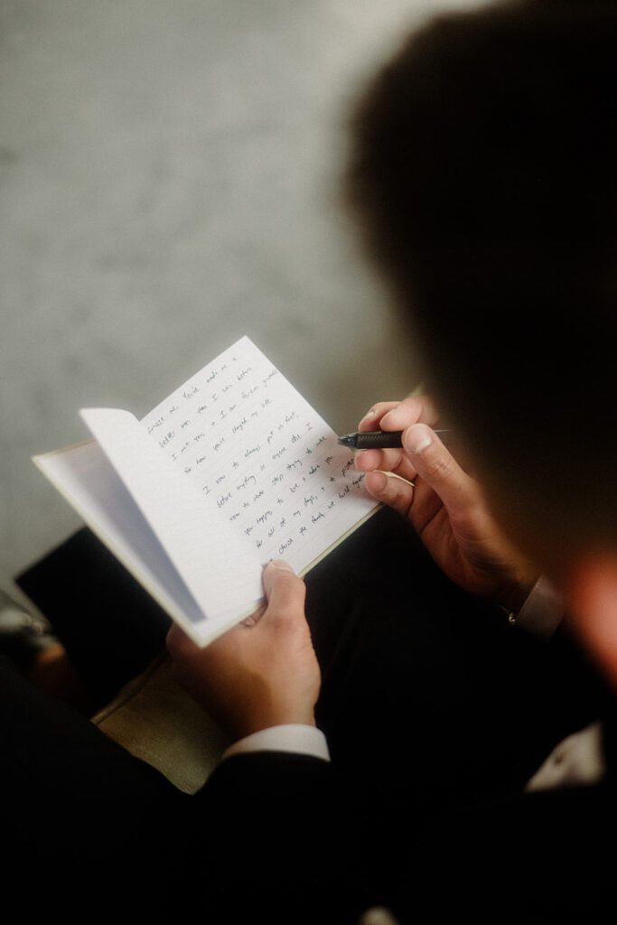 Groom writing his vows in a notebook. 
