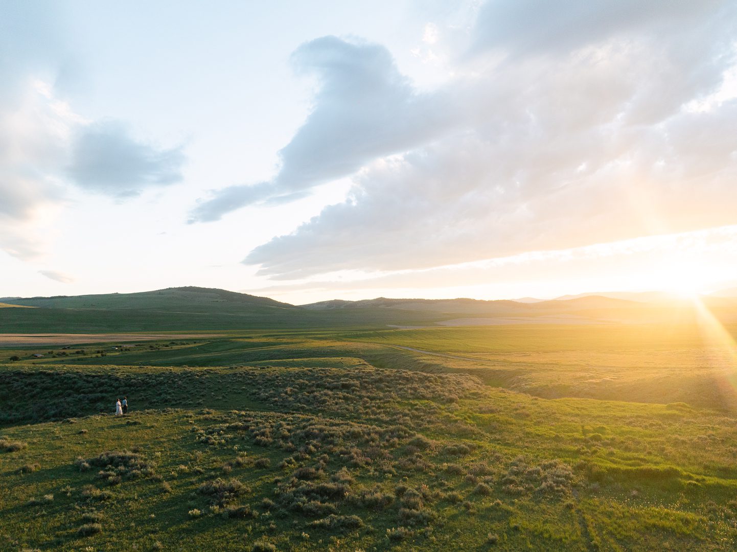 cinematic engagement session photos Montana couple walking in open field at sunset