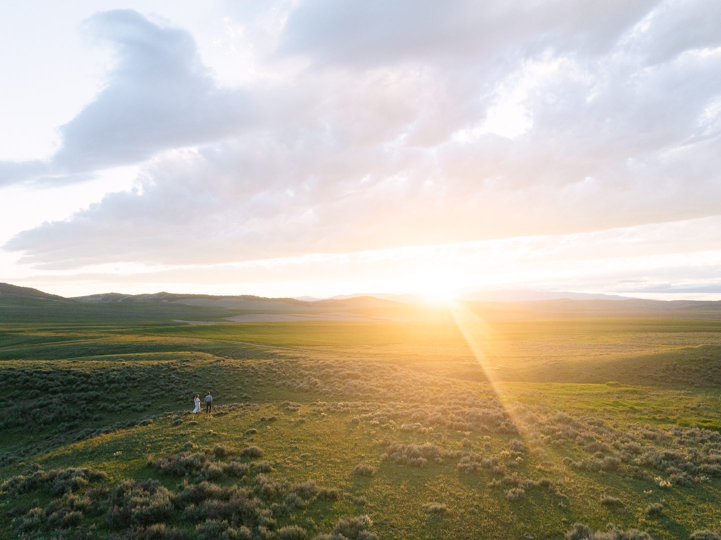 cinematic engagement session photos Montana couple walking in open field at sunset